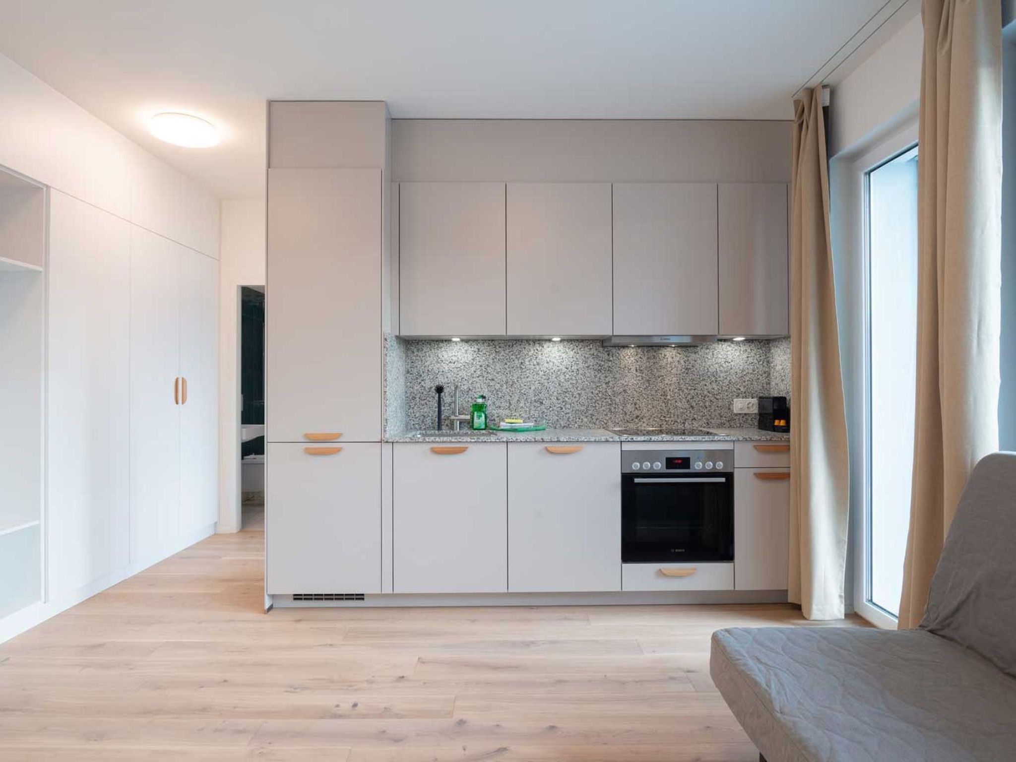Ett modernt kök med vita skåp, en inbyggd ugn och en stänkskydd av granit.