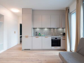 Cozinha moderna com armários brancos, forno embutido e backsplash de granito.