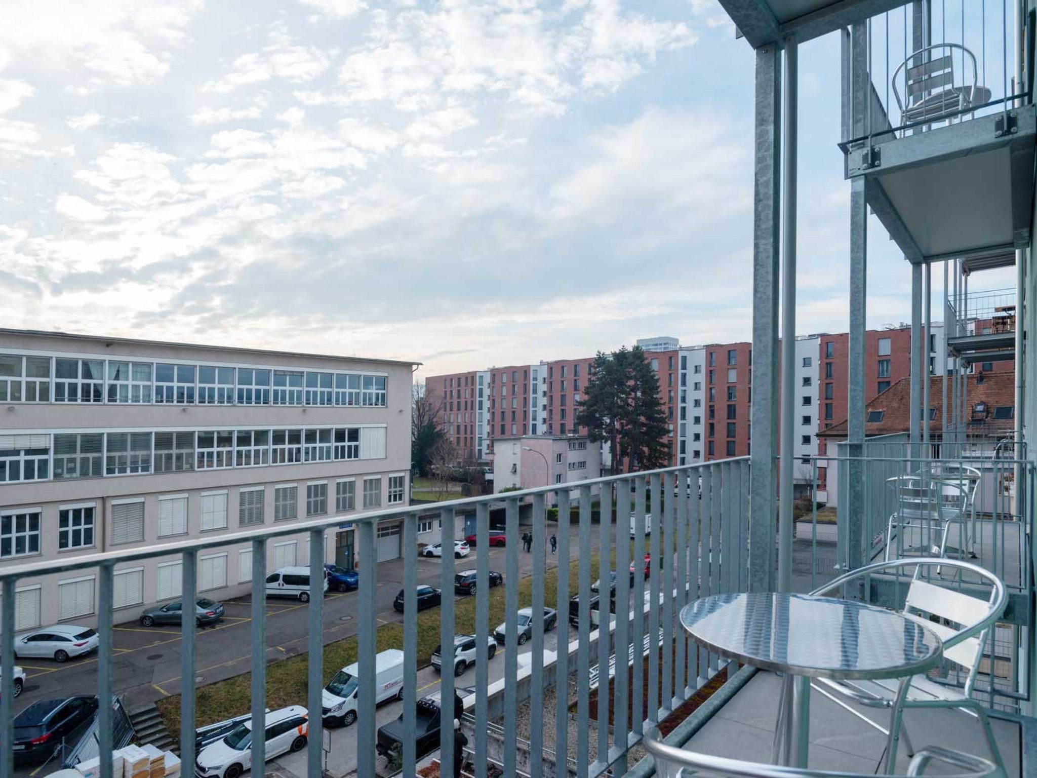Ein Balkon mit Blick auf einen Parkplatz und Gebäude.