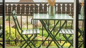 A balcony with a view of a lake, a table with chairs, and a vase with dried plants. - LakeView 1 - Premium Annecy - Veyrier du lac (Veyrier-du-Lac)