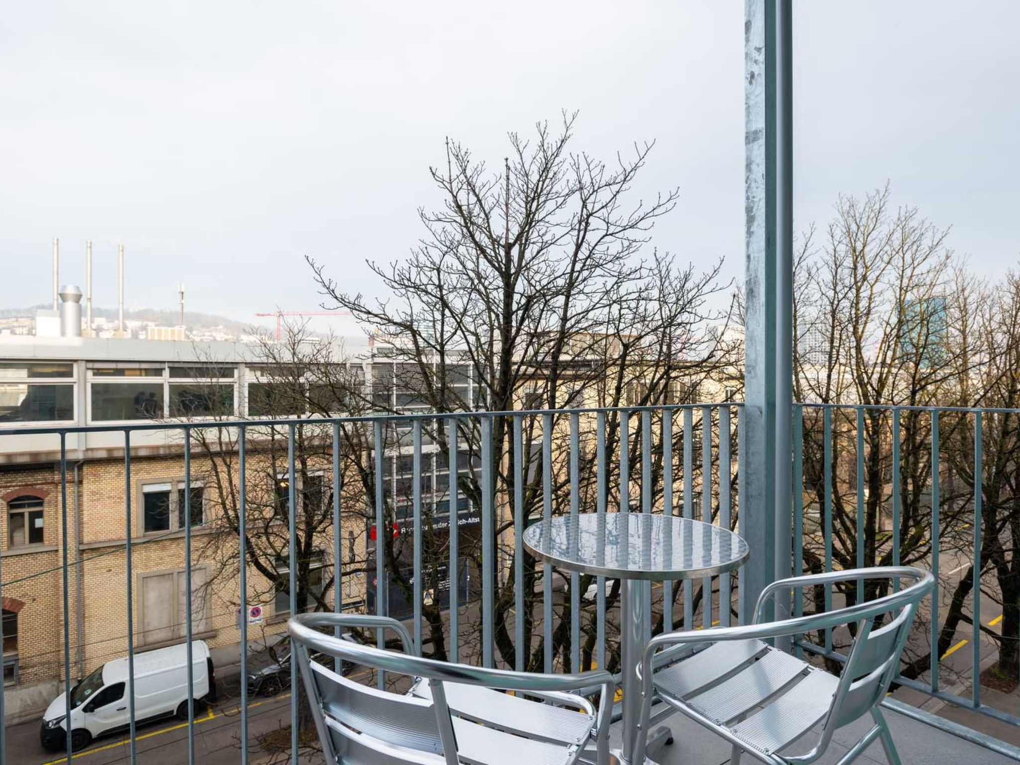Ein Balkon mit Metallgeländern, einem runden Tisch und zwei Stühlen.