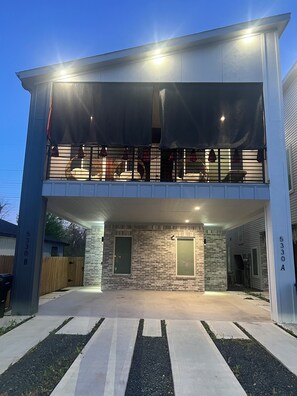 Ein zweigeschossiges Gebäude mit Balkon, Garage und einer Ziegelaußenwand.