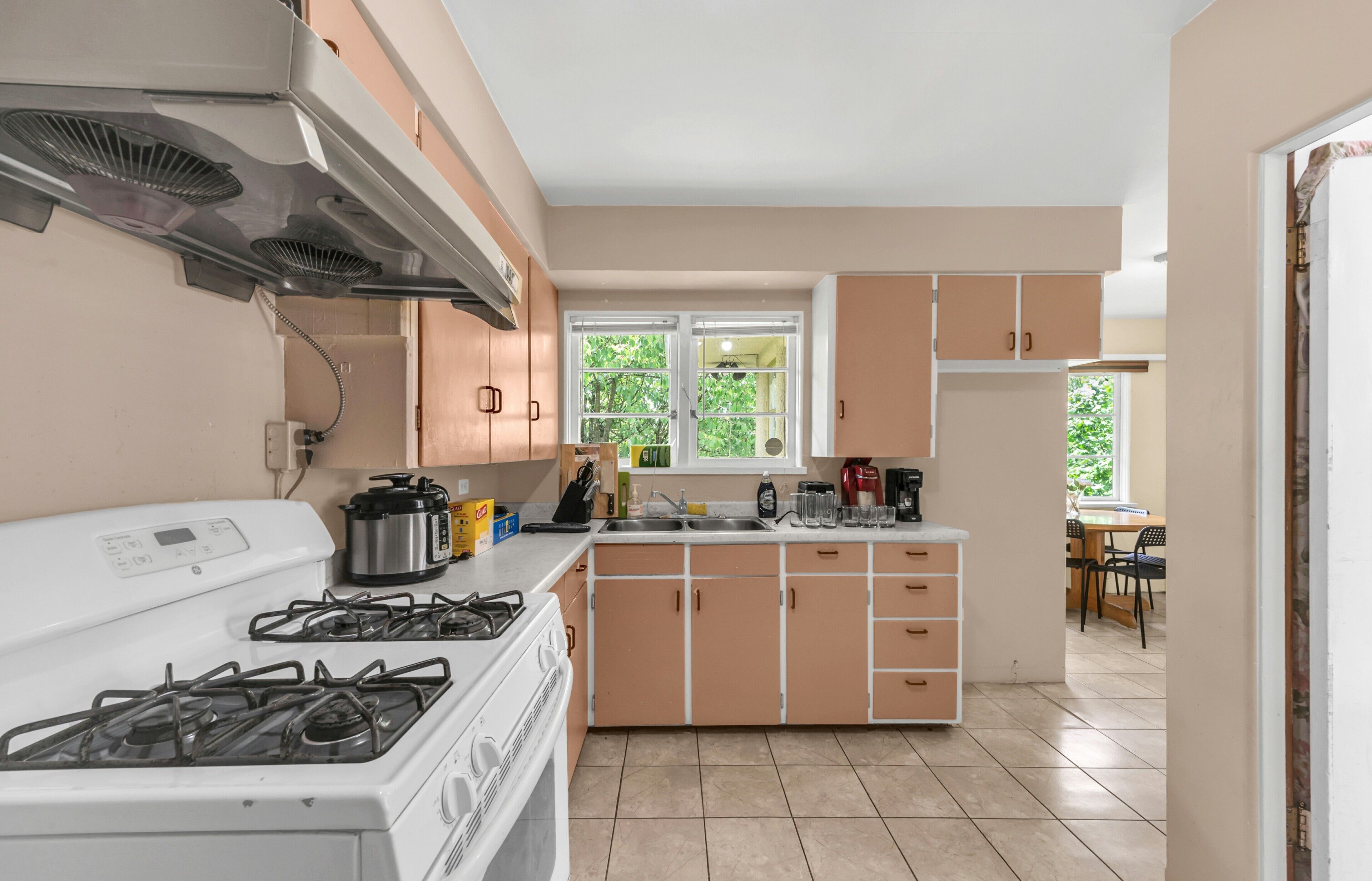 A kitchen with a stove, sink, and cabinets.