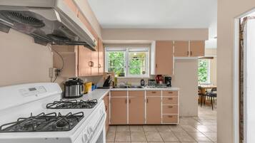A kitchen with a stove, sink, and cabinets.