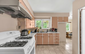 A kitchen with a stove, sink, and cabinets.