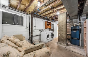 A laundry room with a washing machine, dryer, and a brick wall.