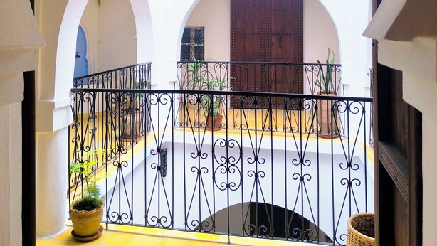 An arched corridor with a decorative lantern, a metal railing, and potted plants.