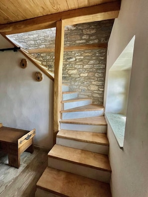 A wooden staircase with stone walls and a bench.