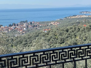 A coastal town with a view of the sea, surrounded by olive groves and red-roofed buildings.
