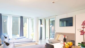 A modern hotel room with a bed, seating area, dining table, and a TV. - Apartment  by Interhome (Lucerne)