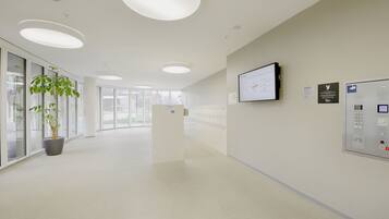 A spacious hallway with a reception desk, a mounted screen, and a control panel.