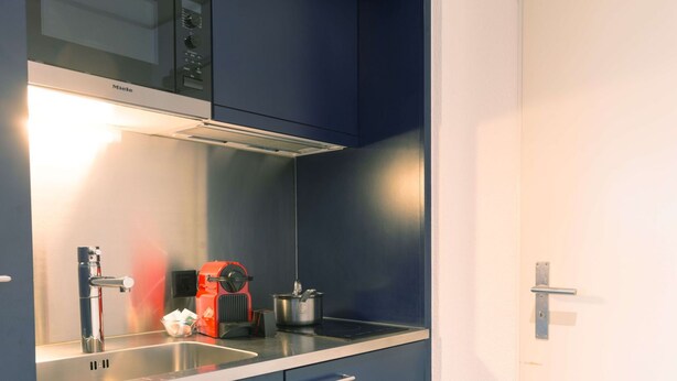 A kitchenette with a built-in stove, a sink, and a microwave. - Apartment  by Interhome (Lucerne)