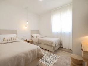 A bedroom with two beds, a bedside table, a lamp, and a window with curtains. - Seaview Villa Grota with a heated pool by Interhome (Rovanjska)