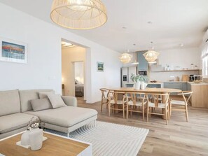 A modern living room with a sofa, dining table, and chairs, a kitchen in the background, and a large window. - Seaview Villa Grota with a heated pool by Interhome (Rovanjska)