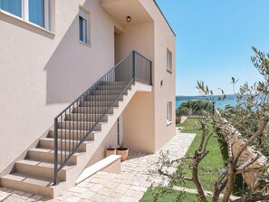 A modern building with a staircase leading to a balcony, surrounded by a well-maintained garden and a view of the sea. - Seaview Villa Grota with a heated pool by Interhome (Rovanjska)