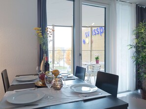 Ein Essbereich mit einem Tisch für zwei Personen, einer Blumenvase und Blick ins Freie.