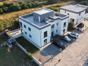 Un bâtiment moderne à deux étages, doté d’un toit plat, d’un espace de stationnement et d’un petit jardin.