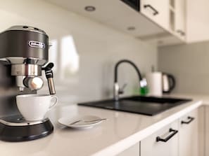 A De'Longhi espresso machine with a cup and saucer on a kitchen counter. - Apartment Laurel near the sea by Interhome (Nin)