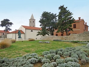 A church with a bell tower, a statue, and a garden with lavender bushes. - Apartment  by Interhome (Nin)