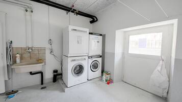 A laundry room with two washing machines, a sink, and a window.