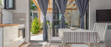 A modern kitchen with a dining area, a TV, and a view of the outdoors.