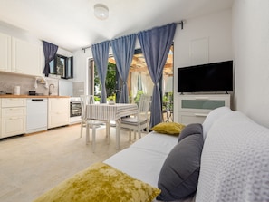 Ein modernes Schlafzimmer mit Bett, Fernseher und einem Essbereich mit Tisch und Stühlen.