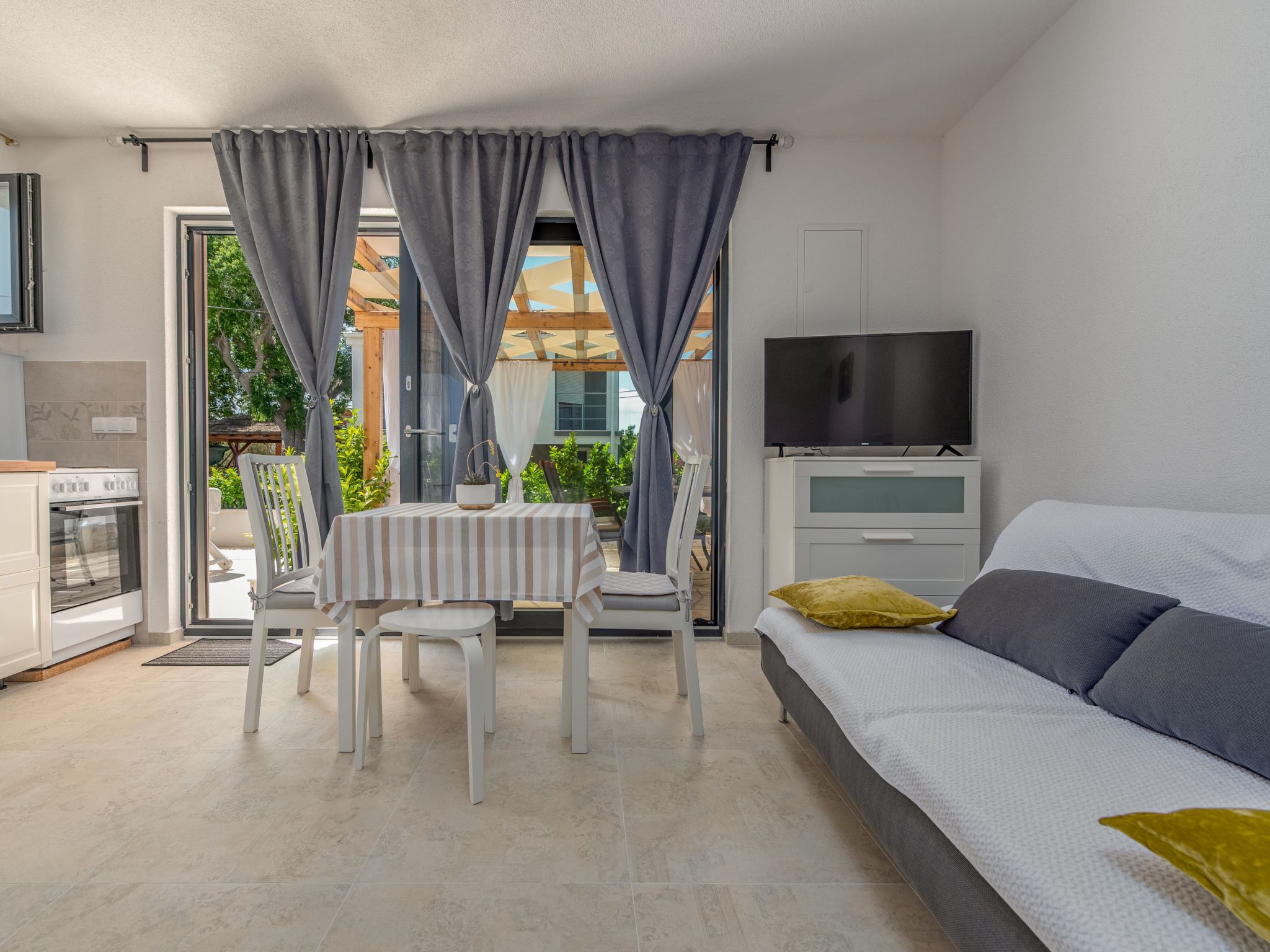 Quarto moderno com uma cama, televisão e área de refeições com mesa e cadeiras.