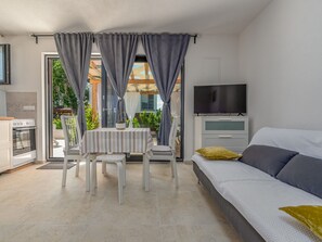Quarto moderno com uma cama, televisão e área de refeições com mesa e cadeiras.