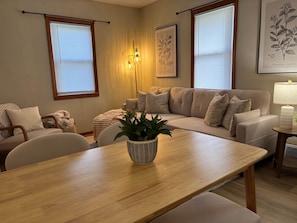 A living room with a sofa, a dining table, and a potted plant.