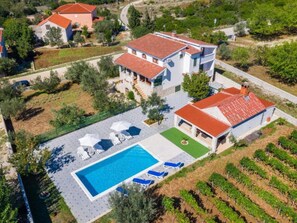 A residential property with a swimming pool, lounge chairs, and a vineyard. - Apartment  by Interhome (Donje Rastane)