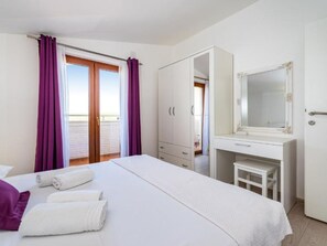 A hotel room with a bed, a desk, a wardrobe, and a balcony with purple curtains. - Apartment Tonka 3+2 by Interhome (Donje Rastane)