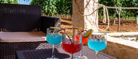 Drei Cocktails auf einem Tisch aus Flechtwerk, im Hintergrund ein Korbstuhl und eine Kordel.