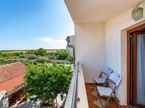 Ein Balkon mit Blick auf eine ländliche Landschaft, zwei weiße Stühle und ein Fliesenboden.