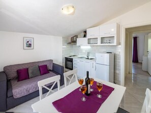 Ein gemütlicher Wohnbereich mit Küchenzeile, einer Essecke mit Tisch für zwei Personen und einem Sofa.