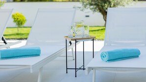 Area piscina con lettini e un tavolino con vassoio contenente bicchieri e caraffa.