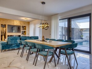 Un espace repas moderne avec une table en bois et des chaises recouvertes d’un tissu turquoise.