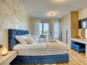 Une chambre moderne avec un grand lit, une table de chevet, un bureau et une vue sur l’extérieur grâce à une porte vitrée.