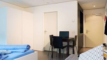A compact room with a bed, a desk with a computer, and a wardrobe.