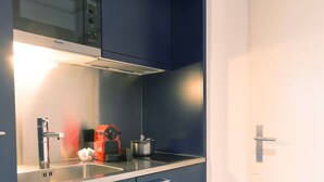 A kitchenette with a built-in stove, a sink, and a microwave. - Apartment  by Interhome (Lucerne)