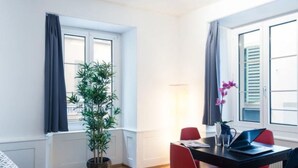 Una habitación con una mesa de comedor, sillas, una planta en maceta y una ventana con cortinas.