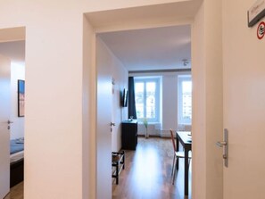 Ein Hotelzimmer mit einem Bett, einem Schreibtisch und einem Stuhl. Ein Fenster bietet Blick auf die Gebäude draußen.