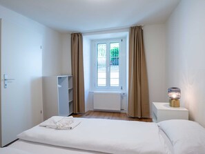 Ein Hotelzimmer mit Bett, Schrank, Heizkörper und einem Fenster mit Vorhängen.