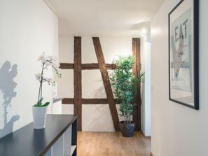 Un pasillo con vigas de madera, una orquídea en maceta y un cartel enmarcado en la pared.