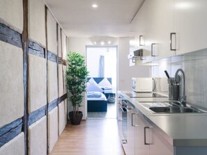 Una cocina moderna con microondas integrado, pileta de acero inoxidable y una planta en maceta.
