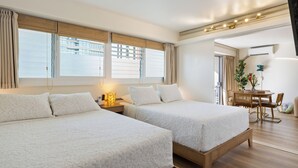 A hotel room with two beds, a dining area, and a view of the city. - Delightful 2-bedroom apartment with AC in vibrant Honolulu (Honolulu)