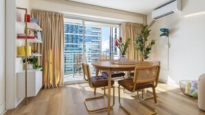 A modern dining area with a round table, chairs, and a view of a cityscape through large windows. - Delightful 2-bedroom apartment with AC in vibrant Honolulu (Honolulu)