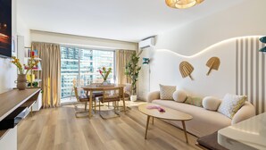 A modern living room with a sofa, coffee table, dining table, and chairs. - Delightful 2-bedroom apartment with AC in vibrant Honolulu (Honolulu)