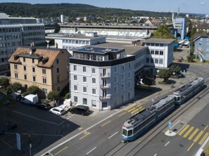 Una estación de tranvía con un edificio moderno, un tranvía y una calle despejada.