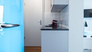 Una cocina compacta equipada con microondas, un refrigerador pequeño y un lavamanos.