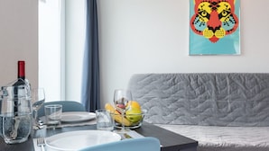Comedor con una mesa dispuesta para dos personas, un cuenco de fruta y una botella de vino.